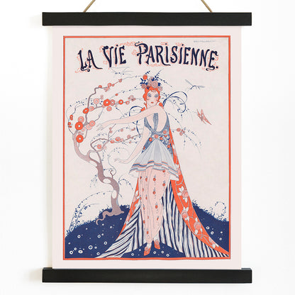Elegant Art Deco poster of a woman in a floral dress standing by a blossoming tree La Vie Parisienne by Umberto Brunelleschi, with wooden magnetic frame on white background