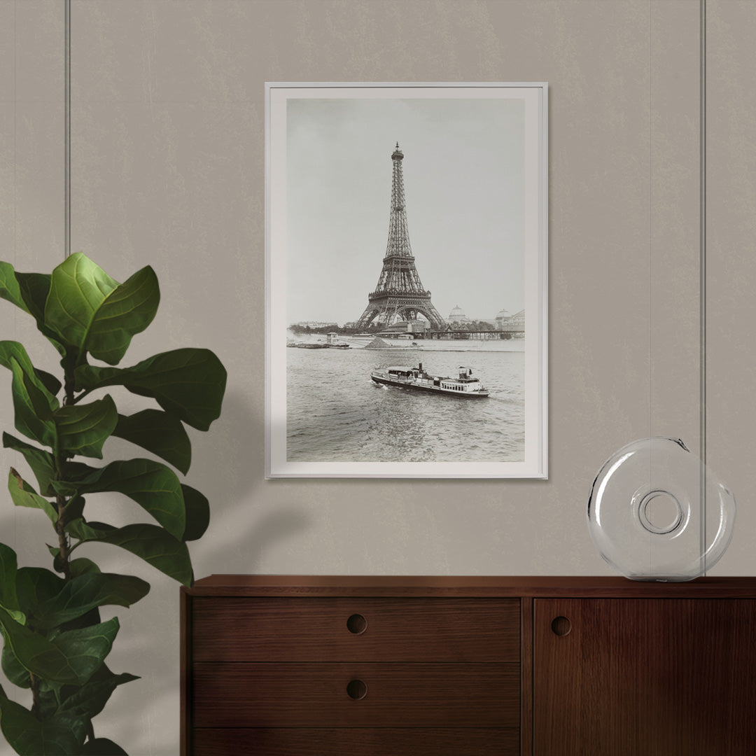Black and white photograph and poster of the Eiffel Tower in Paris with a vintage boat on the Seine river wall decor artwork, framed and displayed in home decor