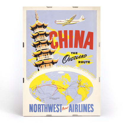 Vintage travel poster of China featuring a pagoda airplane and world map promoting the overland route by Northwest Orient Airlines, framed and displayed in modern living room decor