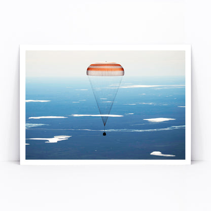 Soyuz MS-02 spacecraft descending with parachute over Kazakhstan NASA poster artwork showing landing, framed and displayed in modern living room decor