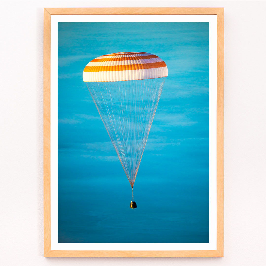 Closeup detail of Soyuz TMA-14M spacecraft descending with parachute against blue sky NASA Expedition 42 landing poster artwork