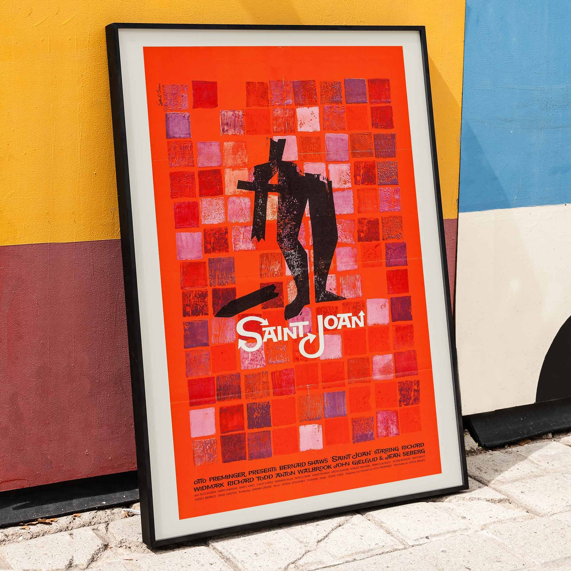 Abstract red and black Saint Joan Movie poster by Saul Bass with stylized figure on checkered background and abstract red squares, framed and displayed in home decor