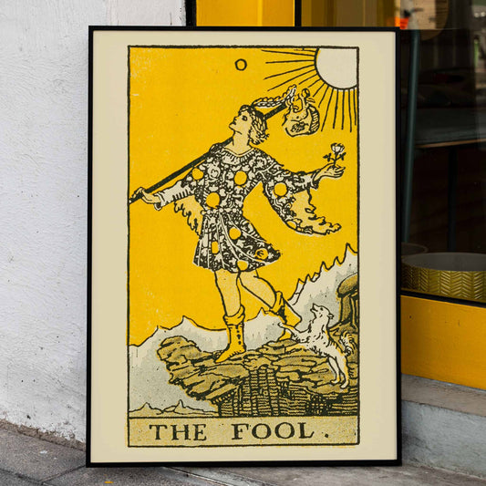 The Fool tarot card by Lauron William de Laurence showing a whimsical figure and dog on a cliff with a bright yellow background, framed and displayed in home decor