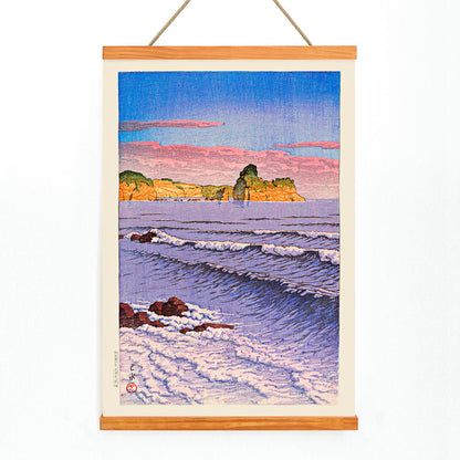 Colorful seascape waves and rocky shore with ocean waves and coastal cliffs in Morning Sea at Bikuni in Shiribeshi Province by Kawase Hasui under a colorful sky, with wooden magnetic frame on white background
