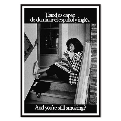 Young woman reading and smoking on stairs in bilingual anti-smoking poster by US Department of Health and Human Services titled Usted es capaz de dominar el español y inglés and you are still smoking, with black aluminium frame on white background